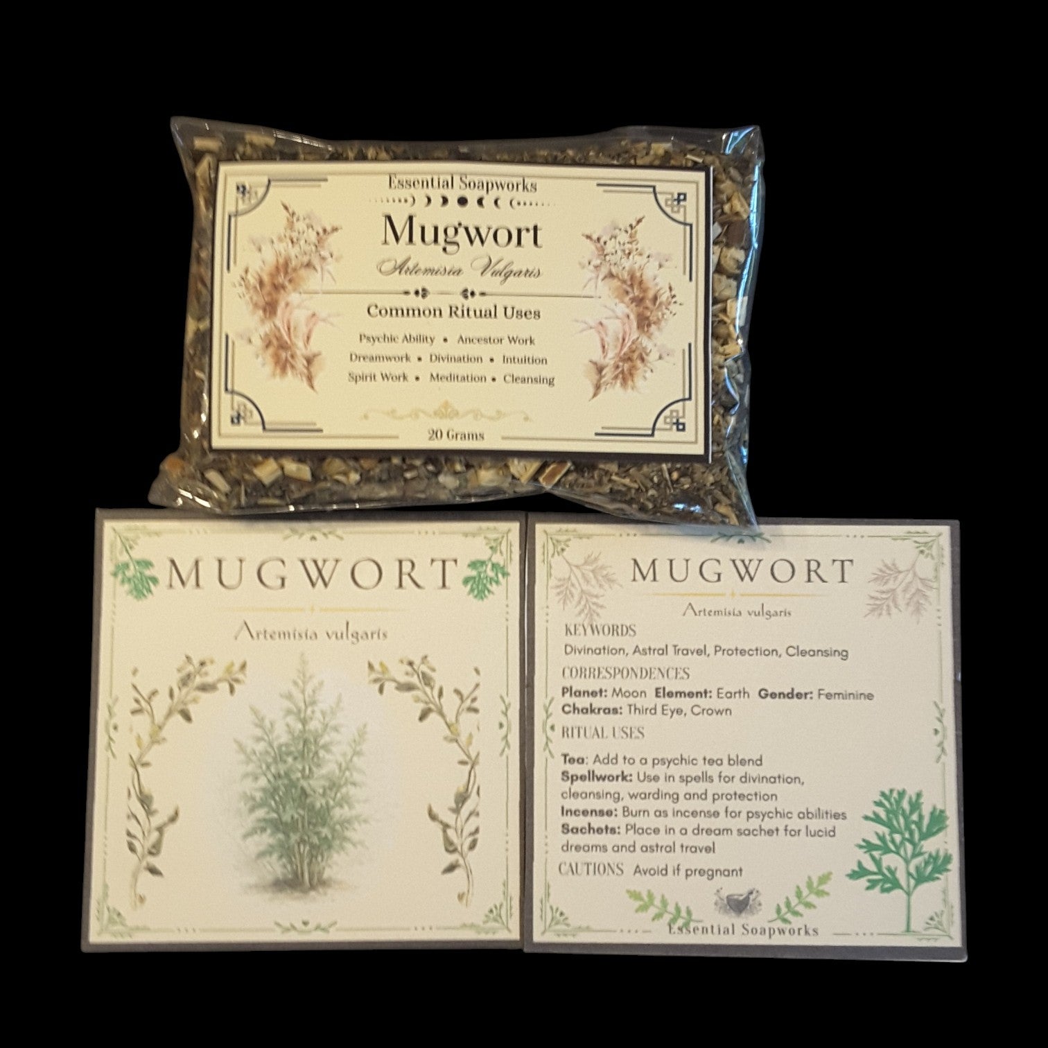 Mugwort herb product set on a black background, including a clear plastic bag of dried mugwort leaves with a cream label, and two printed cards displaying mugwort information and illustrations.