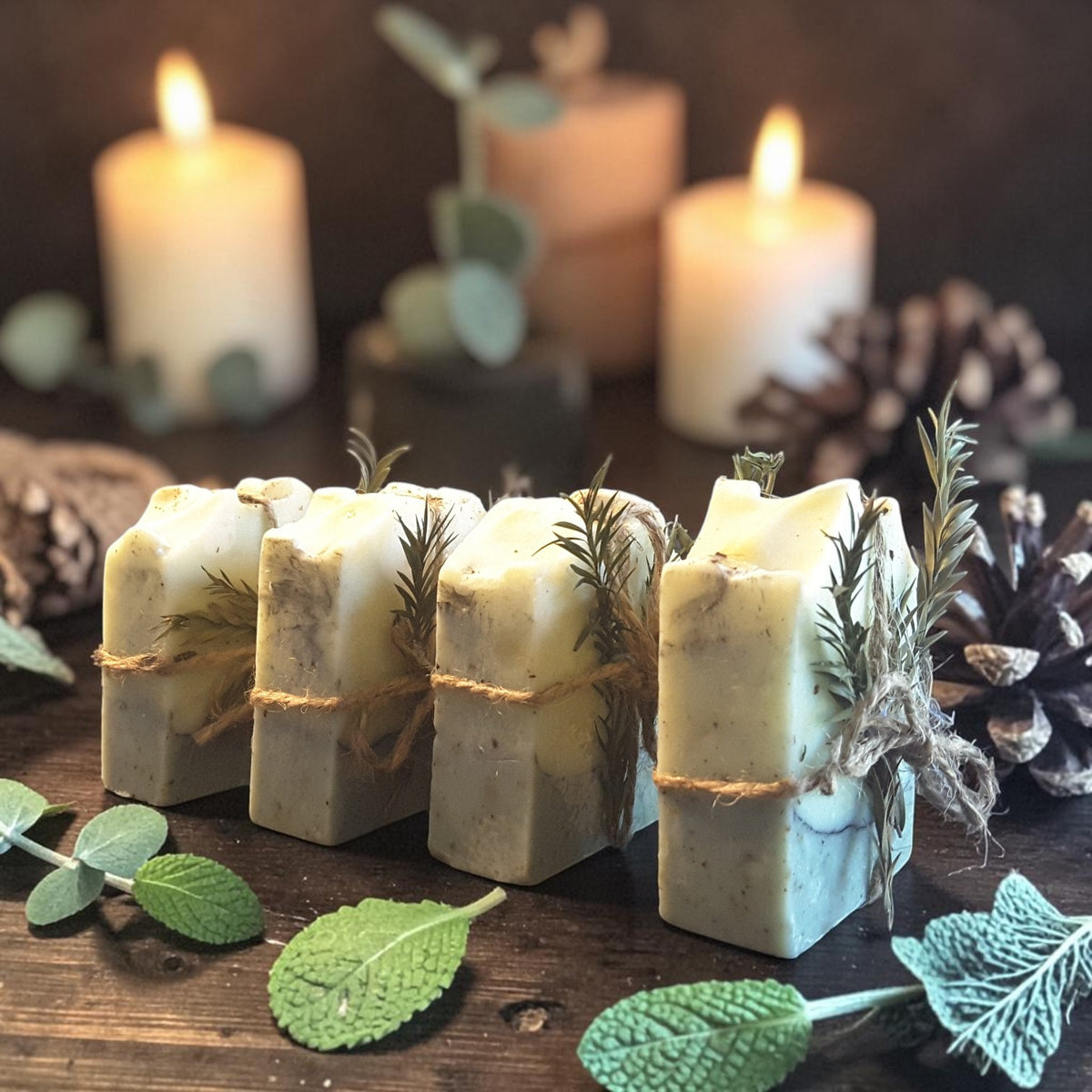 eucalyptus mint christmas botanical soap on a dark wooden surface with pine cones and holly with candles in the background