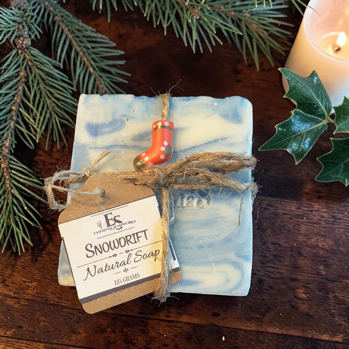 snowdrift christmas soap on a wooden surface with pine cones and pine needles with a candle in the background