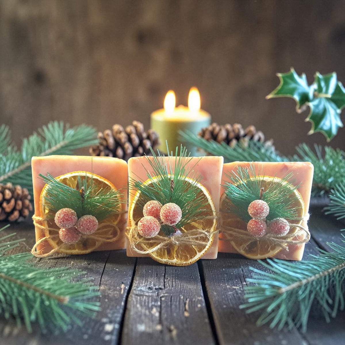 cranberry orange christmas soap on a wooden surface with pine needles and cranberries and candles in the background