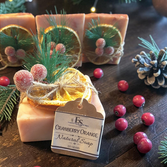 cranberry orange christmas soap on a wooden surface with pine needles and cranberries