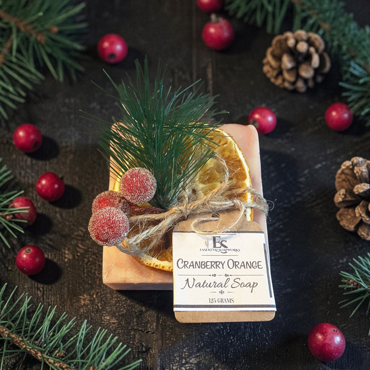 cranberry orange christmas soap on a wooden surface with pine needles and cranberries