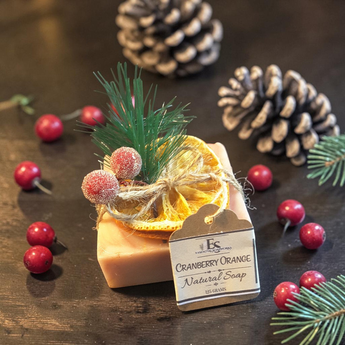cranberry orange christmas soap on a wooden surface with pine needles and cranberries