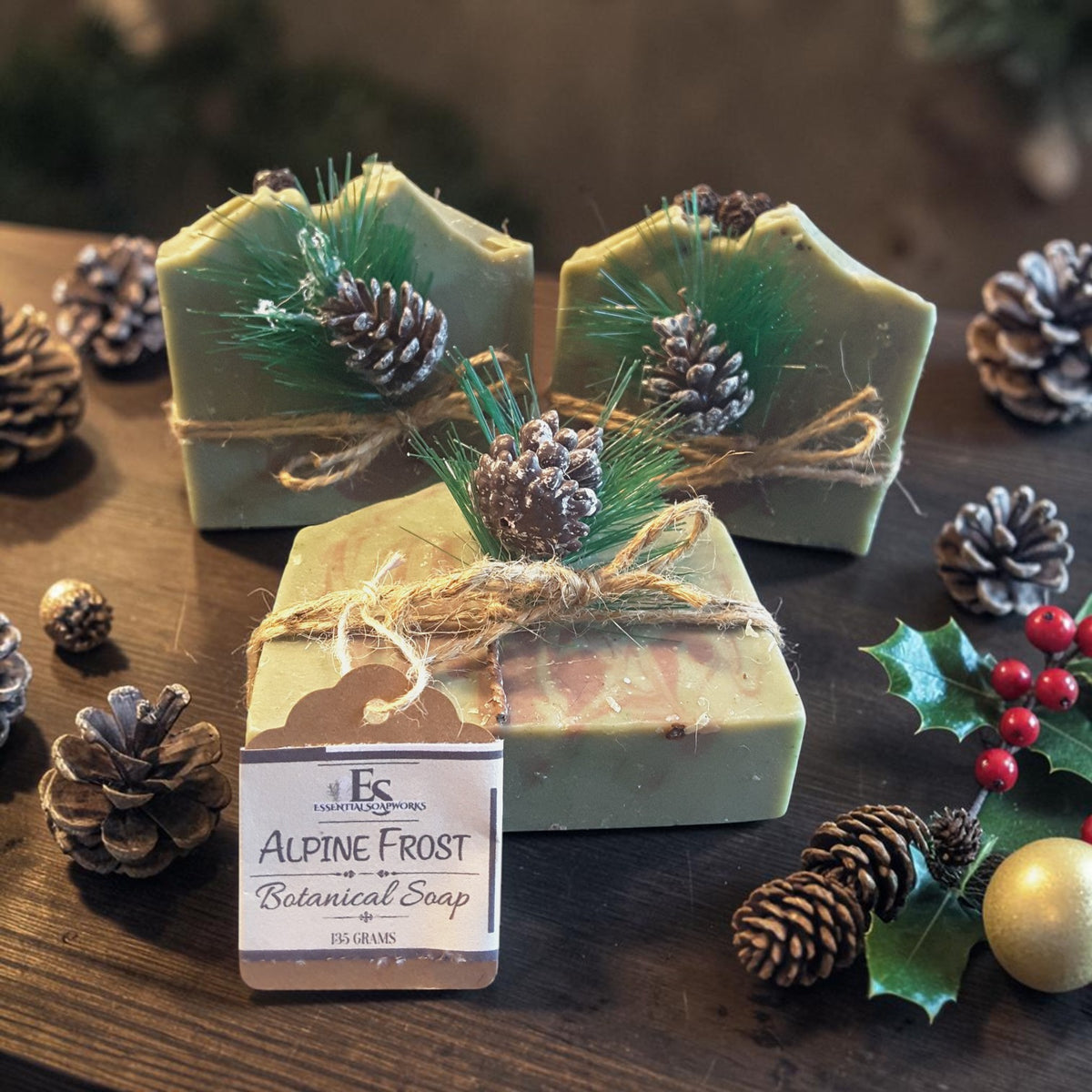 three bars of alpine frost christmas soap on a wooden surface with pine cones
