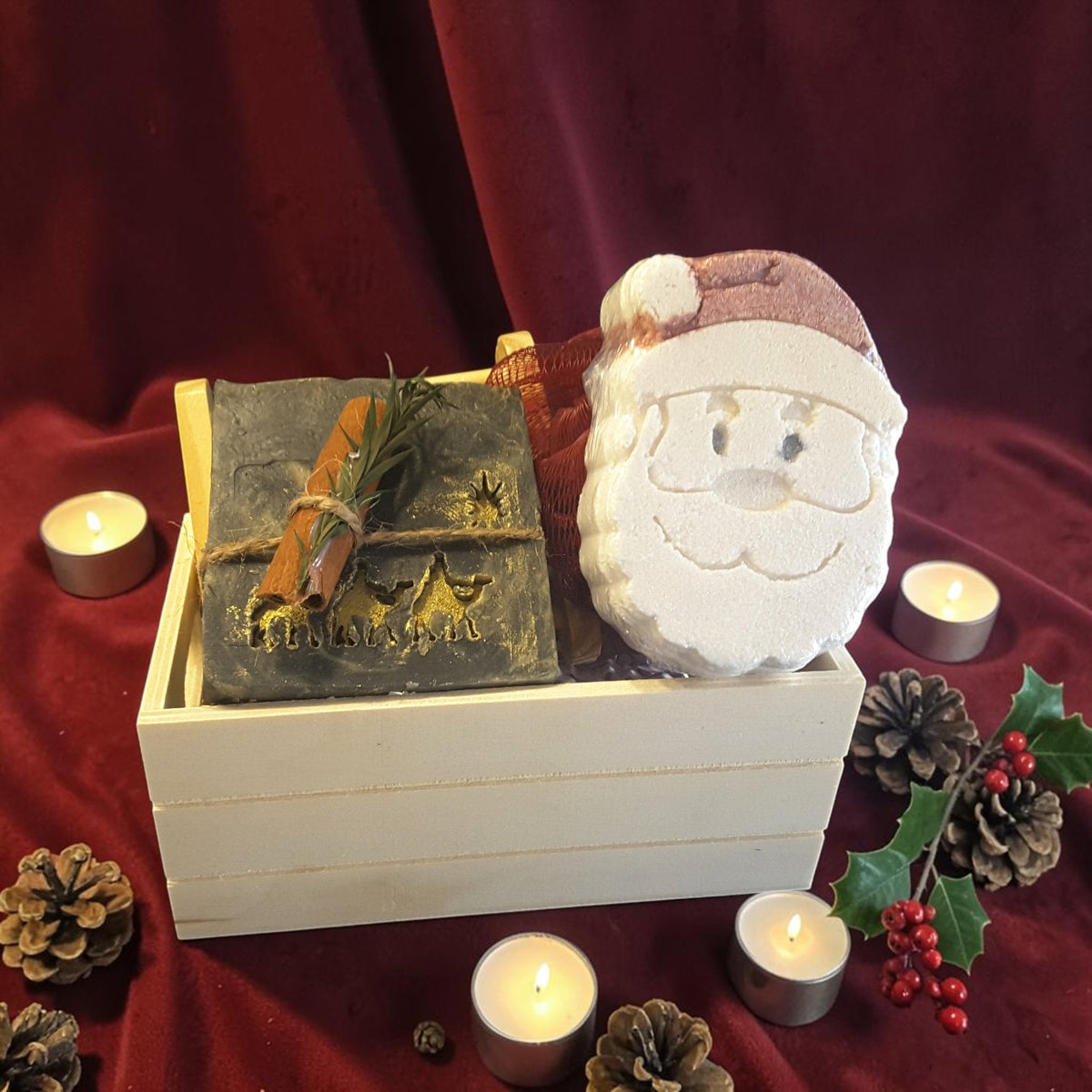 winter solstice christmas gift crate spa set featuring winter solstice soap, santa shaped bath bomb, bamboo soap ladder and loofah in a wooden crate on a red fabric surface 