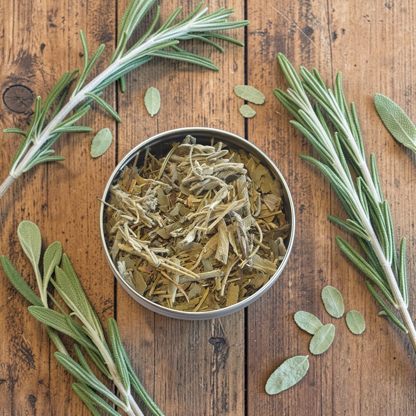 Energy Cleanse loose incense in a metal container surrounded by fresh rosemary on a wooden surface