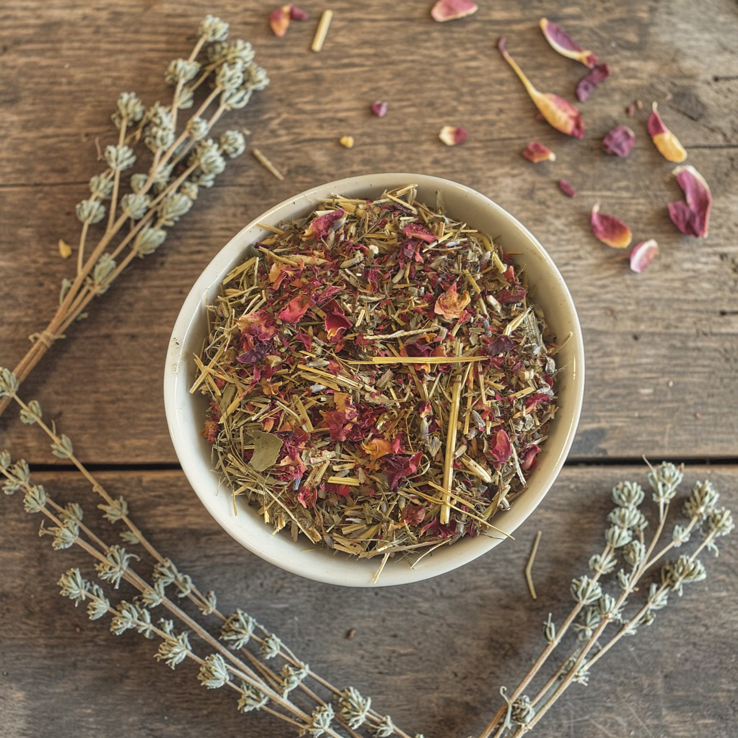 Evening wind down tea in a bowl on a wooden surface with dried herbs and flowers.