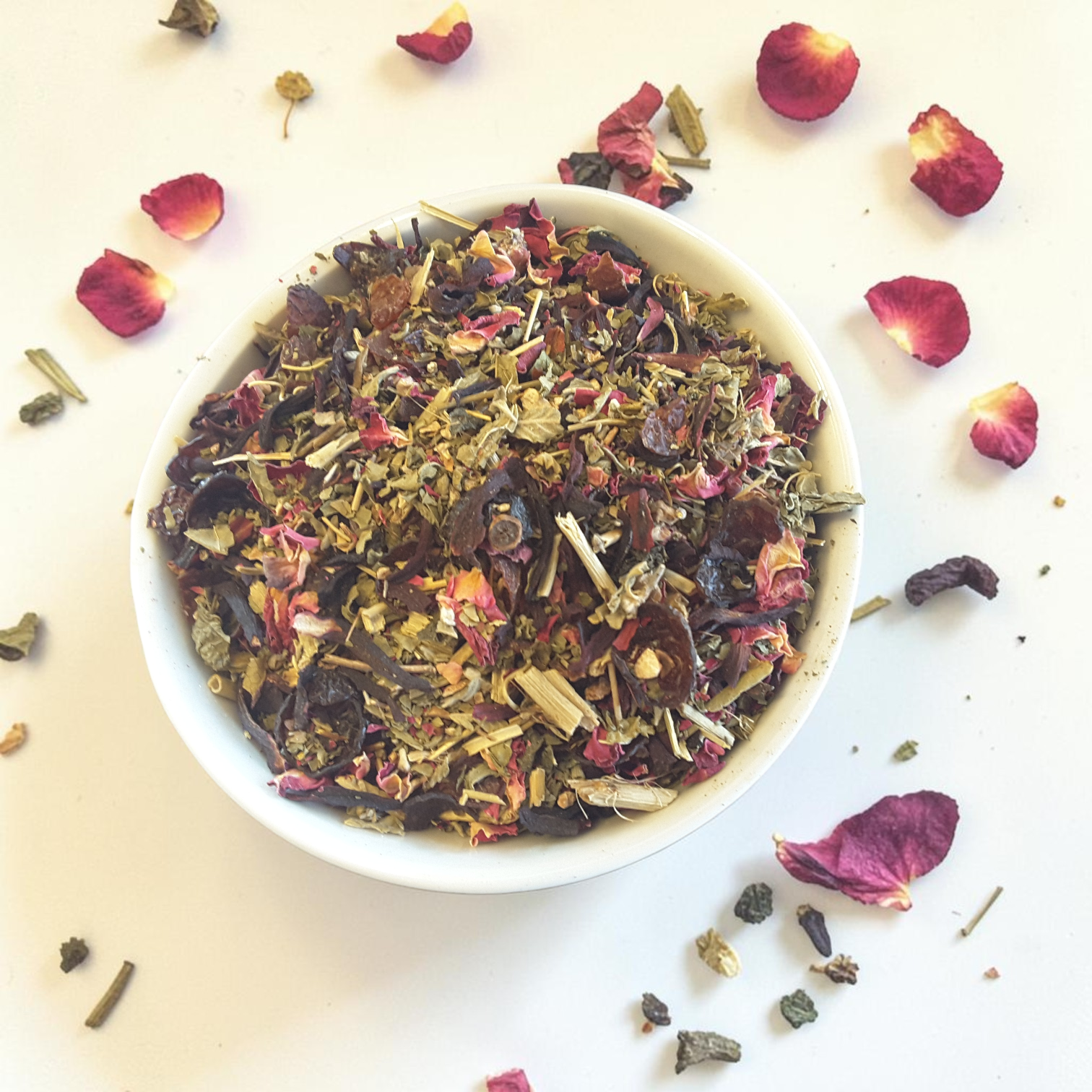 Love spell tea mix in a white bowl with dried rose petals on a light background