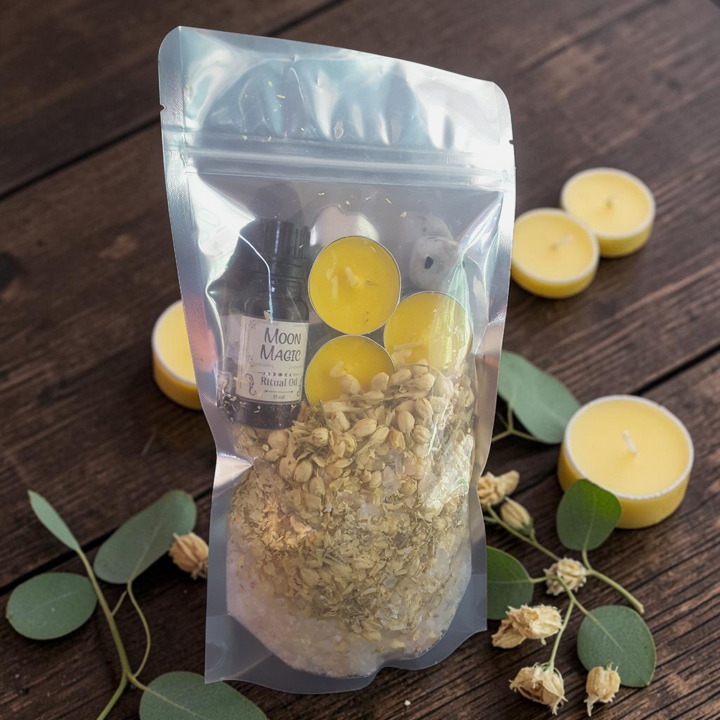 Moon Magic Bath Ritual Kit with bath salts, jasmine, ritual oil, tealight candles and moonstone crystal on a wooden surface