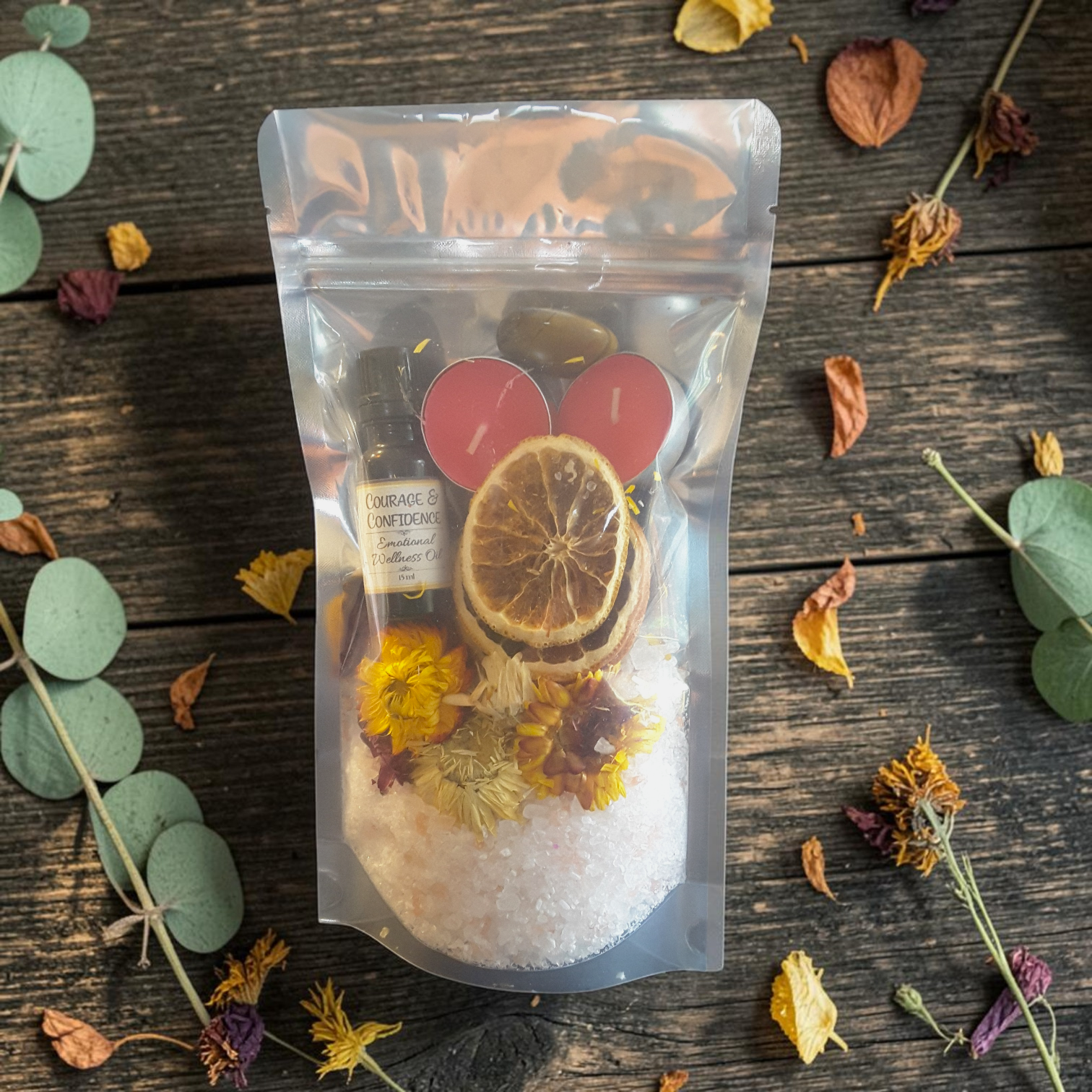 Confidence & Vitality Bath Ritual Kit with tealight candles, flowers, orange slices, tiger's eye crystal and ritual oil on a wooden surface