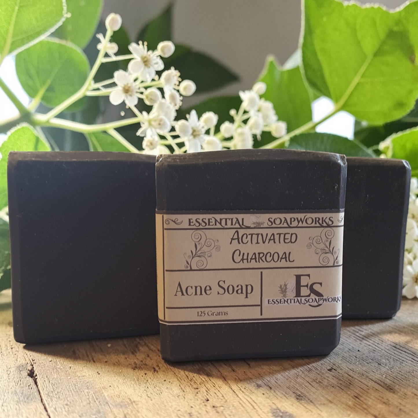 activated charcoal acne soap on a doily on a wooden surface with white flowers