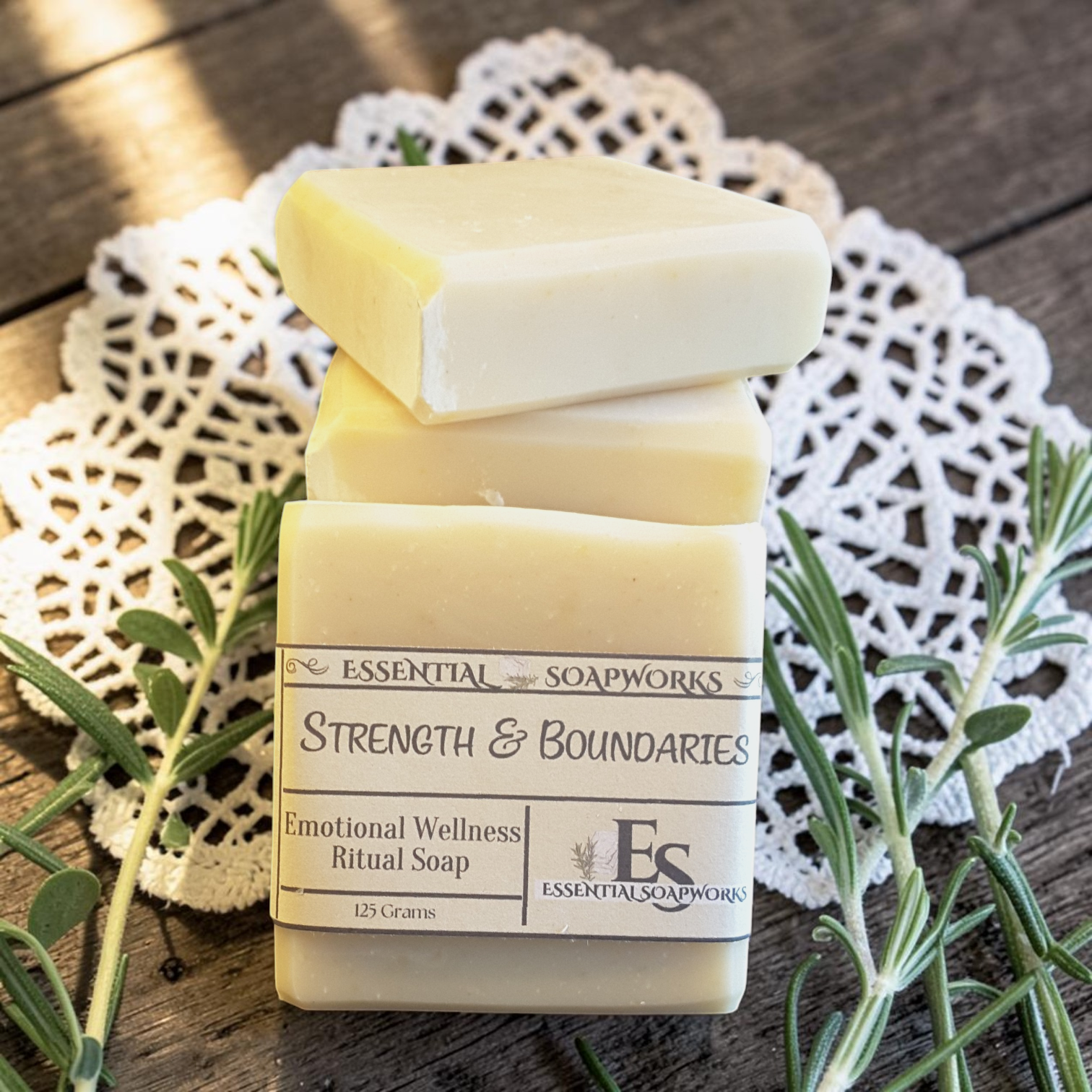 Strength & Boundaries Emotional Wellness Soap on a white doily, surrounded by green leaves on a wooden surface.