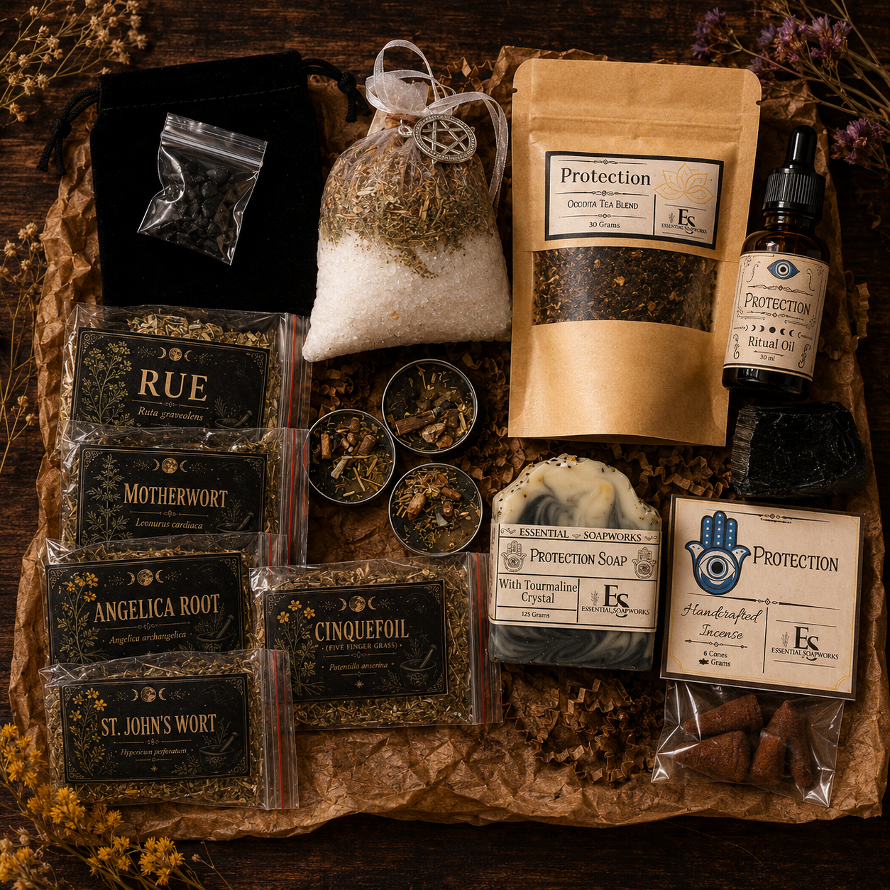 A flat-lay arrangement of a Samhain Ritual Kit on a rustic brown paper tray over a dark wood surface. The set includes a black velvet pouch, a bag of salt and herbs, a kraft pouch of Protection Organic Herbs, a dropper bottle of Protection Salve, several packaged herbal teas or infusions labeled Rue, Motherwort, Angelica Root, and St.