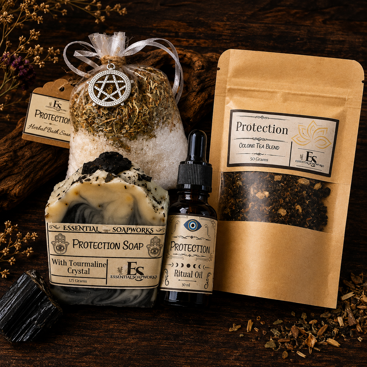 A Samhain Ritual Kit from Essential Soapworks featuring Protection Soap, a bottle of Protection Ritual Oil, and a bag of Colosseum Tea Blend, arranged on a dark wooden background with dried flowers and a black stone.