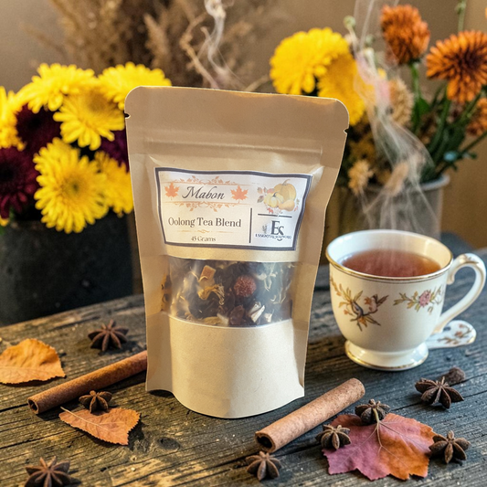 Loose leaf Mabon tea blend on a wooden surface with a cup of tea, cinnamon, star anise and fall leaves with fall flowers in the background