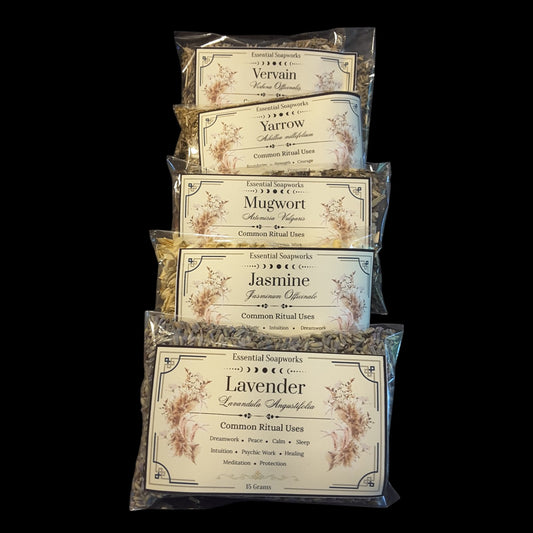 Five clear plastic bags of witchy herbs for divination stacked vertically on a black background. The bags contain lavender, mugwort, yarrow, and vervain with labels for Lavender, Jasmine, Yarrow, and Vervain visible.