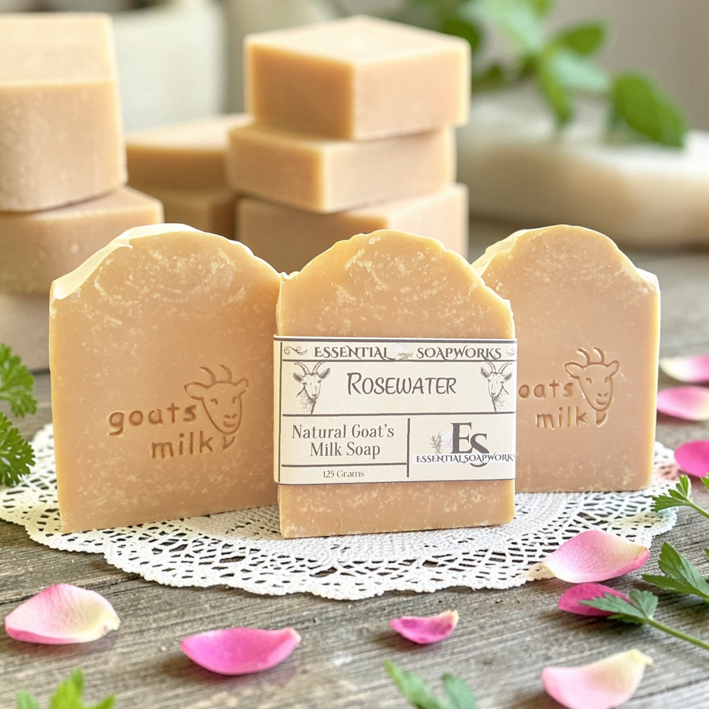 stacks of goat milk soap bars on a doily with pink flower petals