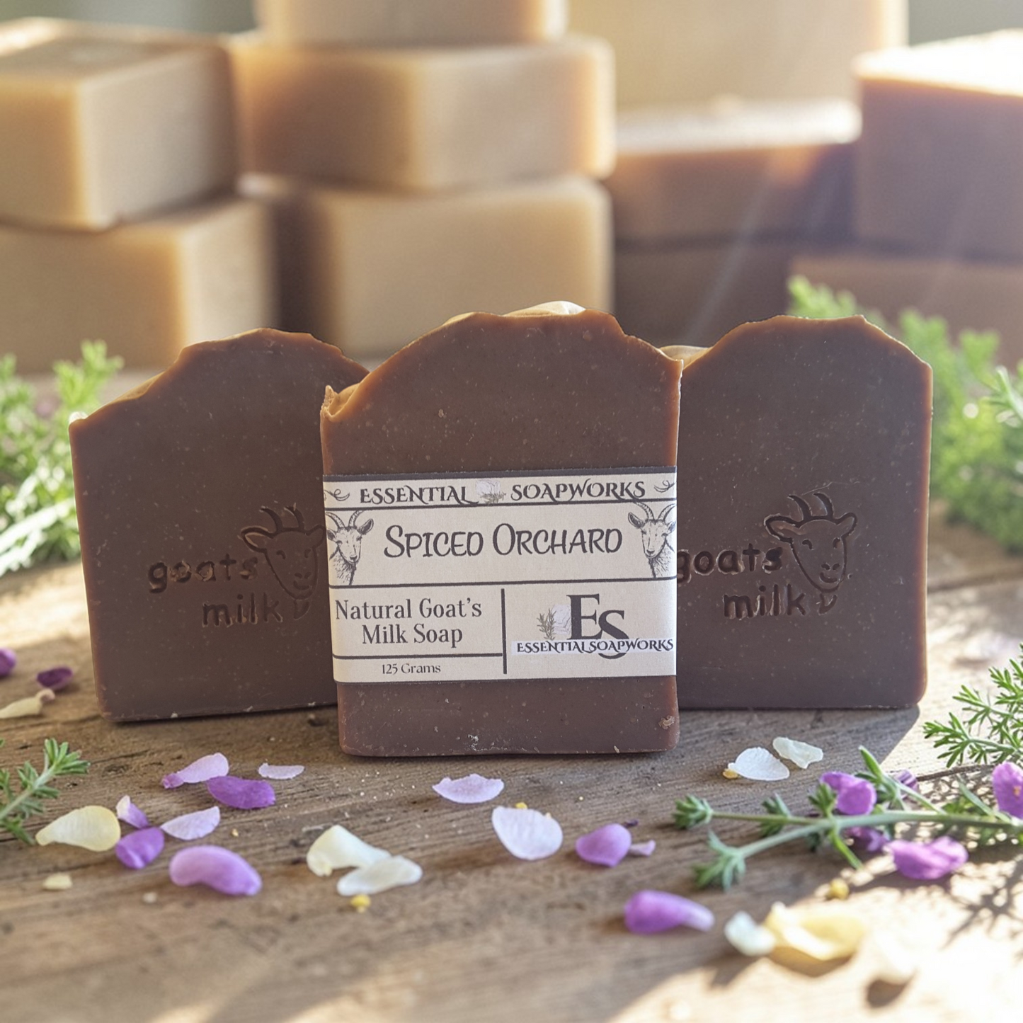 natural goat's milk soap with 'Essential Soapworks' branding on a wooden surface with flowers.