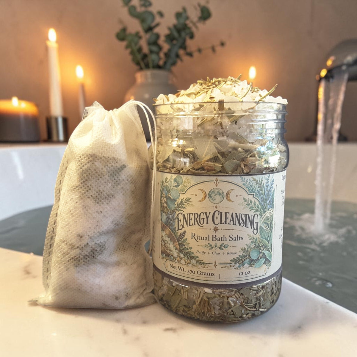 energy cleansing bath salts in a jar next to a muslin bag on the edge of a bathtub with plants and candles in the background