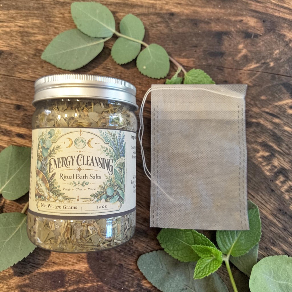 energy cleansing bath salts in a jar on a dark wooden surface next to a muslin bag and mint leaves