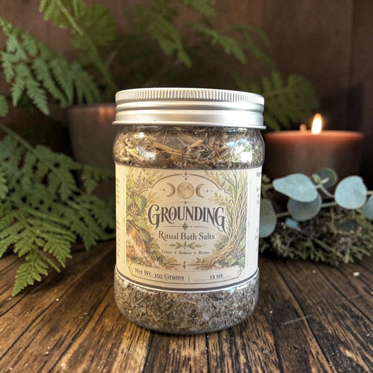 grounding bath salts in a jar on a dark wooden surface with candles and greenery in the background
