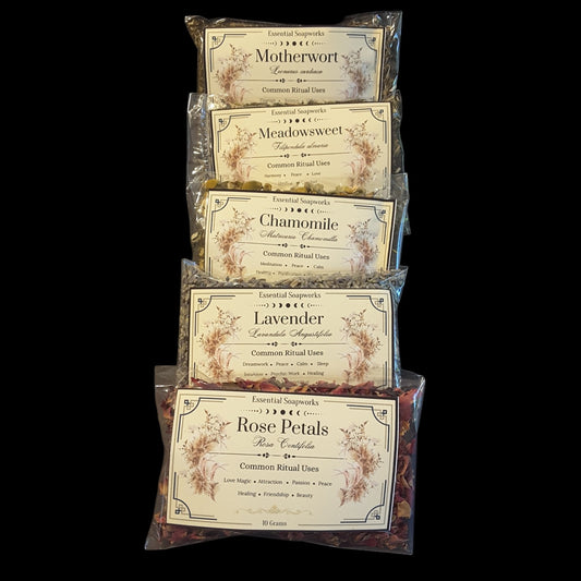 Five clear plastic bags of witchy herbs for peace and tranquility arranged in a vertical stack against a solid black background. The bags feature vintage-style cream labels with floral illustrations and text including 'Motherwort', 'Meadowsweet', 'Chamomile', 'Lavender', and 'Rose Petals'.