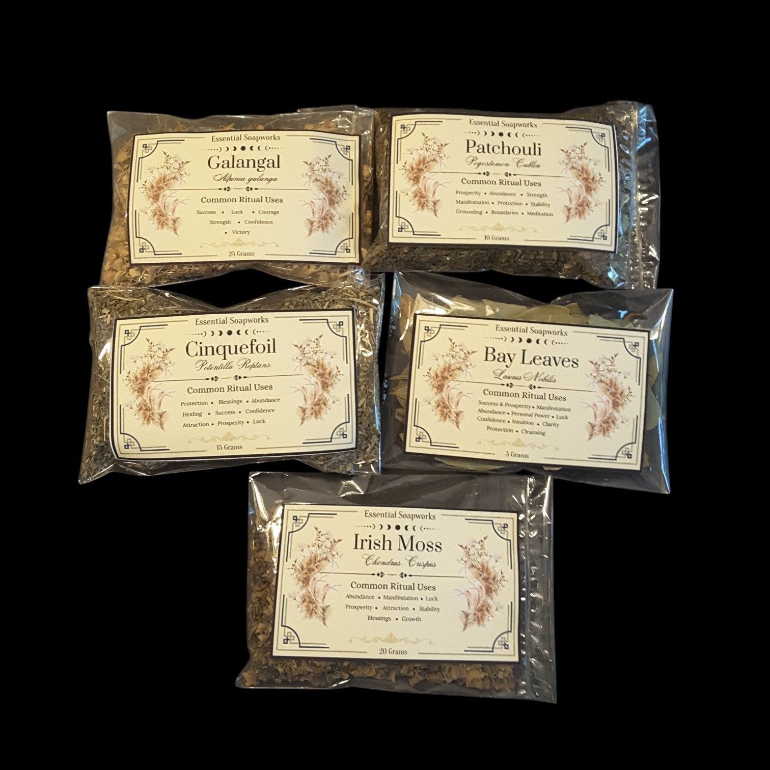 Five clear plastic bags of abundance and manifestation herbs for money magic spells and rituals arranged on a black background, each with a cream label reading a different tea name: Galangal, Patchouli, Cinquefoil, Bay Leaves, and Irish Moss.