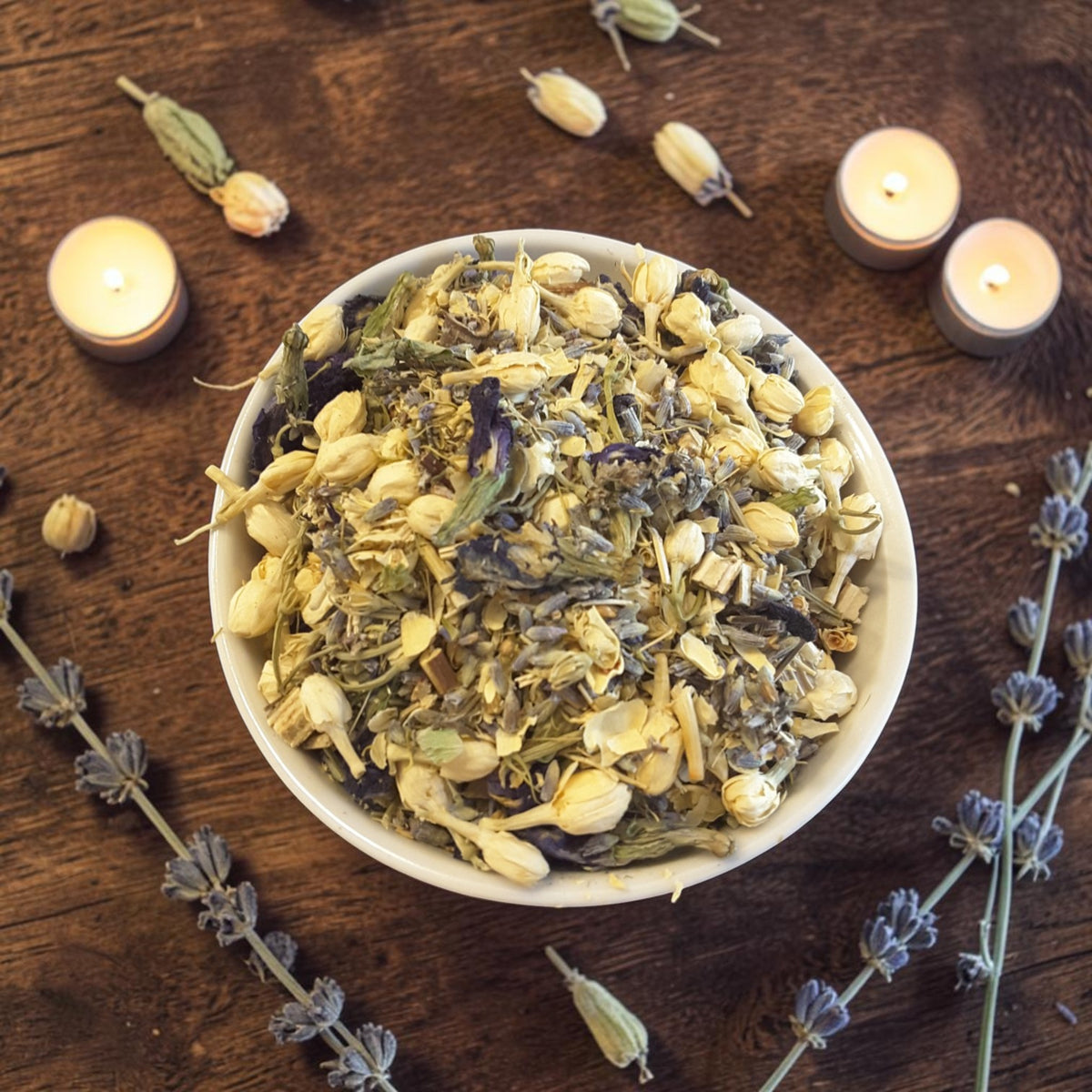a bowl of intuition tub tea on a dark wooden surface with jasmine, lavender and candles
