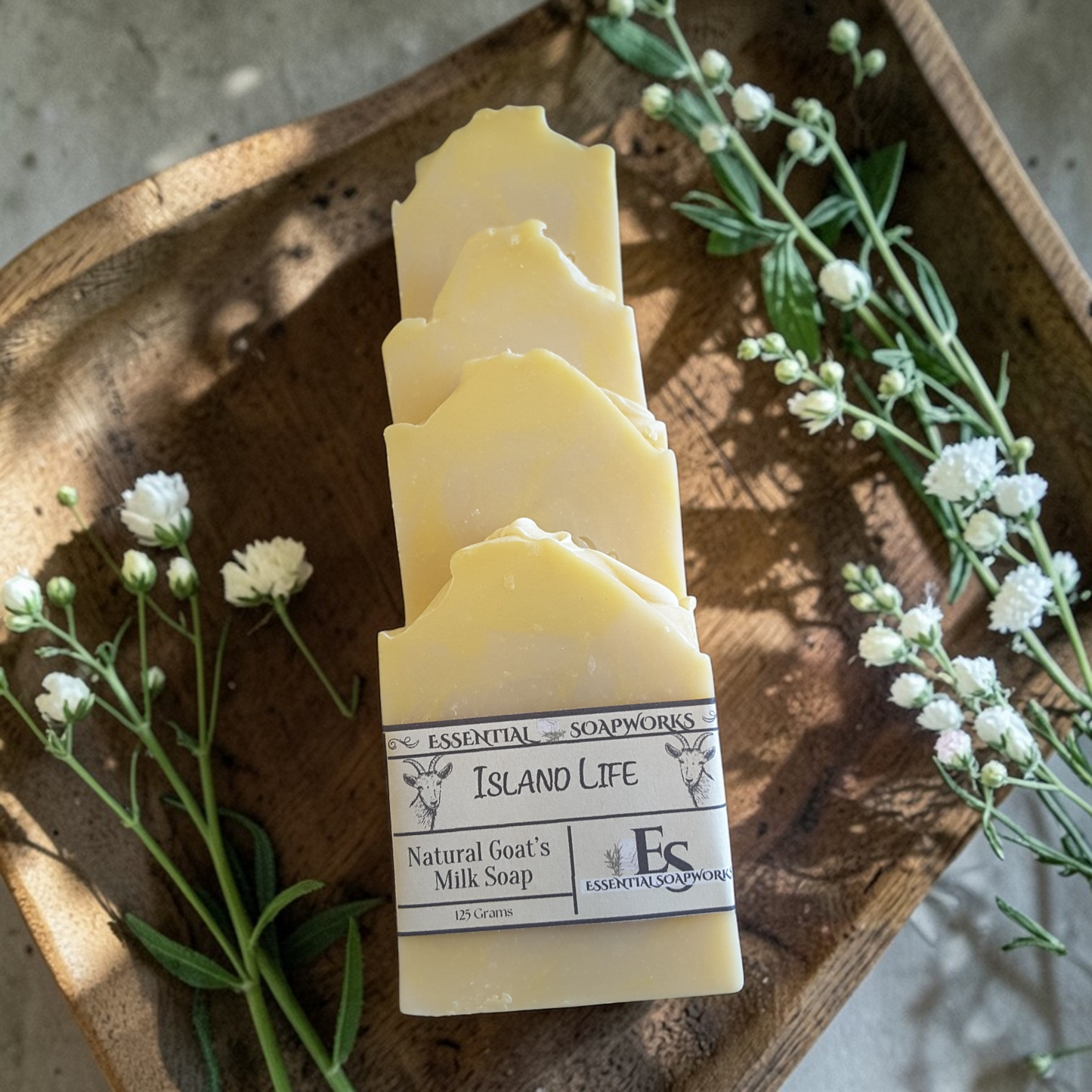 goat milk soap bars on a wooden tray with flowers