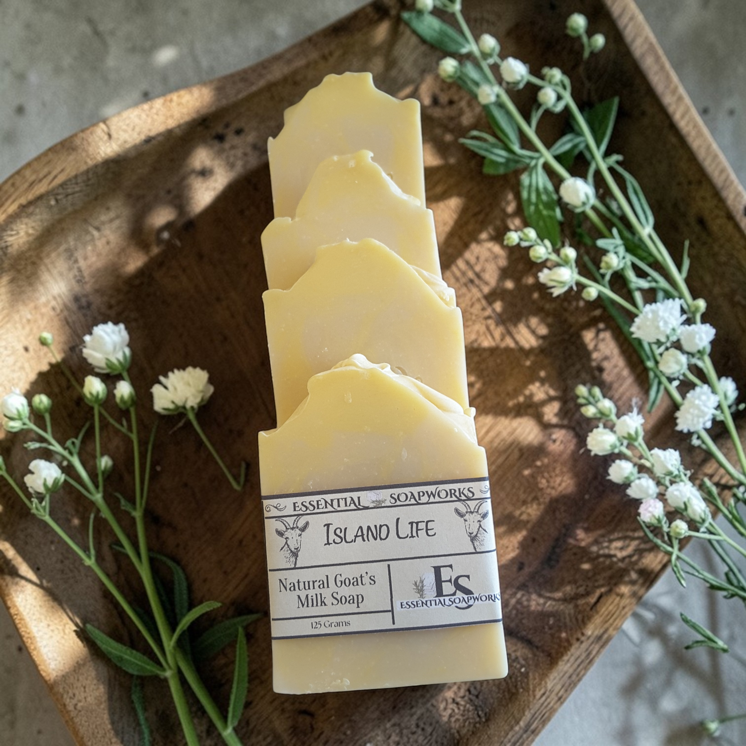 goat milk soap bars on a wooden tray with flowers