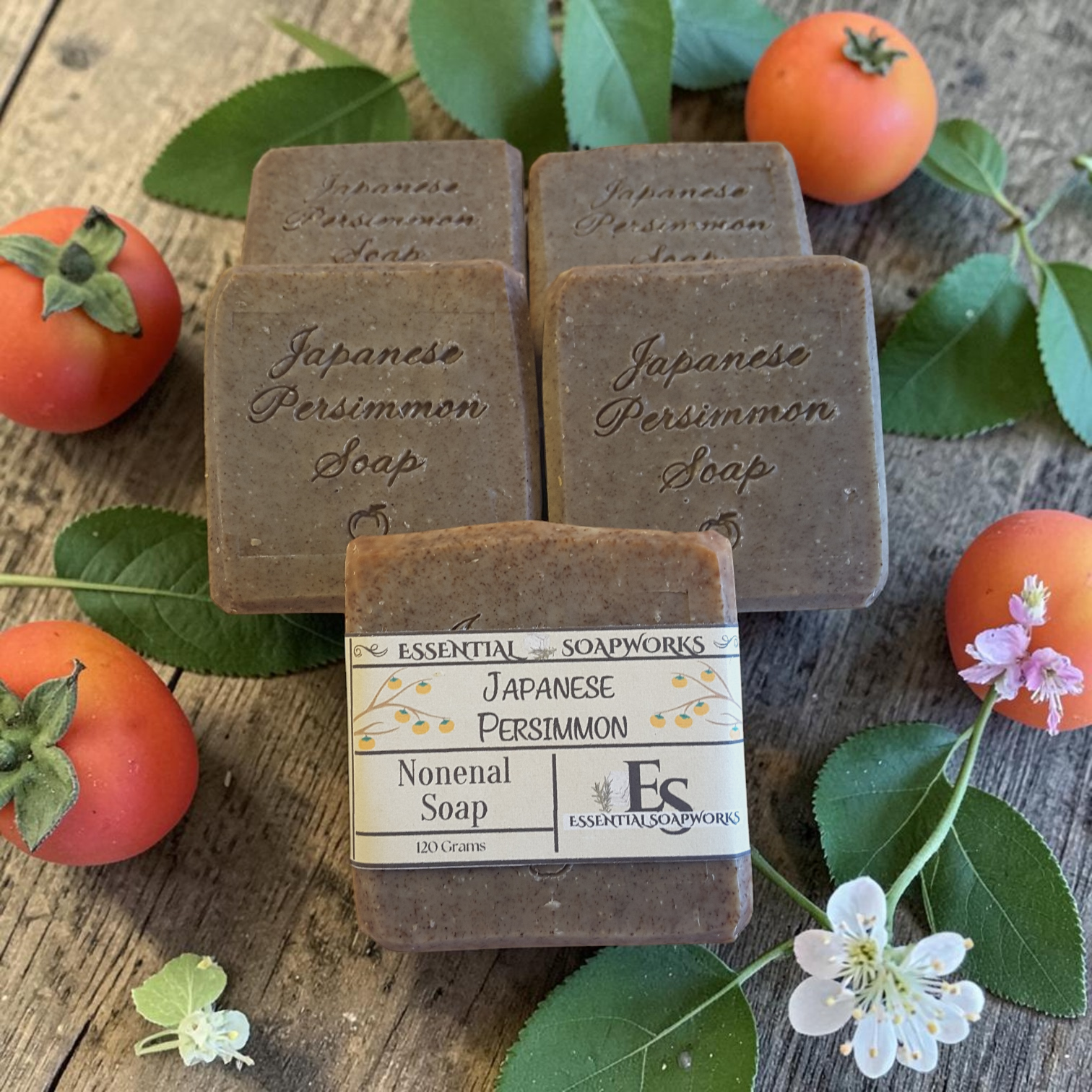 Japanese Persimmon soap bars with persimmon fruits and leaves on a wooden surface