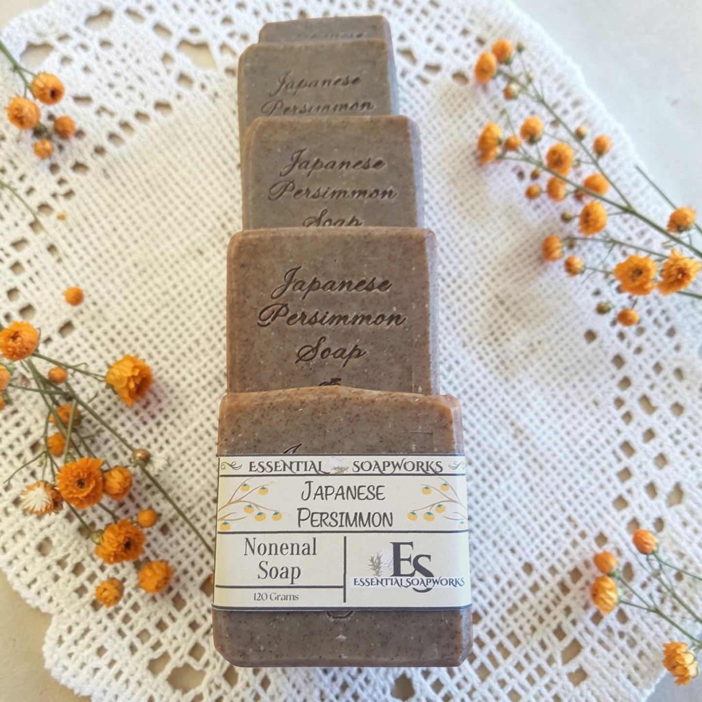 Stack of Japanese Persimmon soap bars with a label on a lace background with flowers.