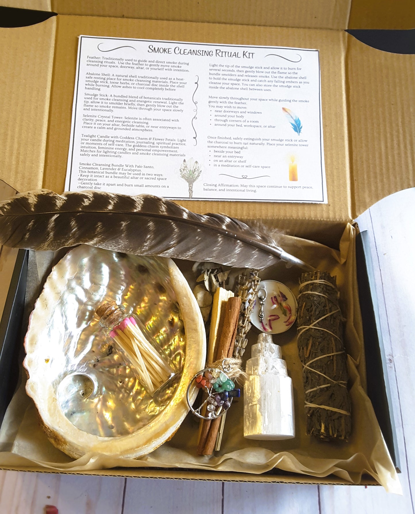 Smoke cleansing ritual kit featuring mugwort smudge stick, abalone shell, selenite crystal tower, candle, and botanicals