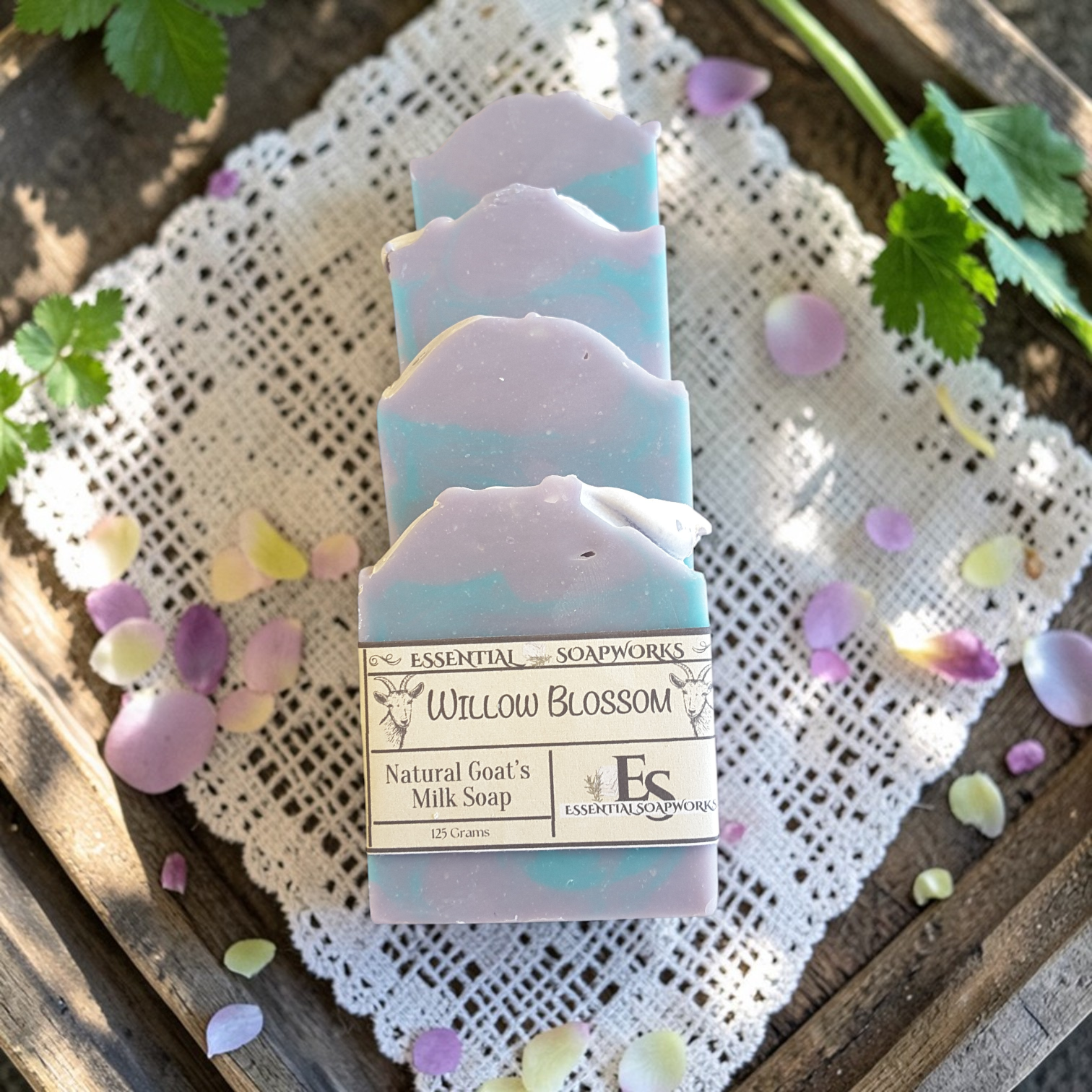 Natural goat milk soap bars on a wooden surface with lace fabric and flower petals