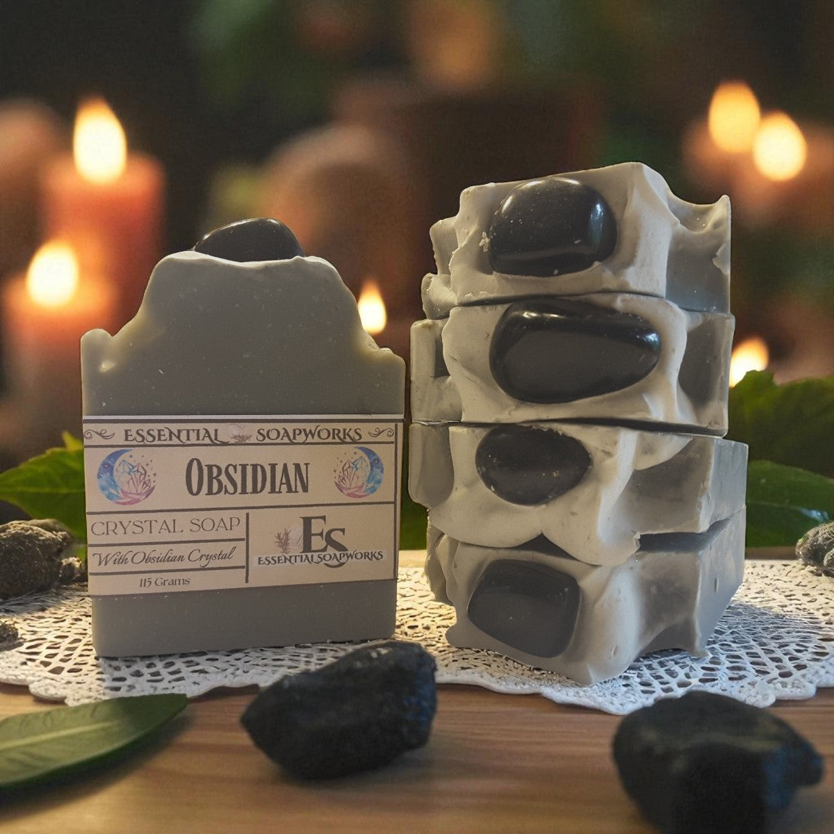 Obsidian crystal soap with decorative packaging on a table with blurred candles in the background