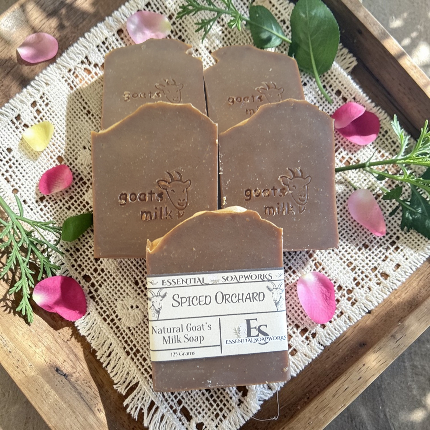 goat milk soap bars on a lace cloth with flowers and greenery.
