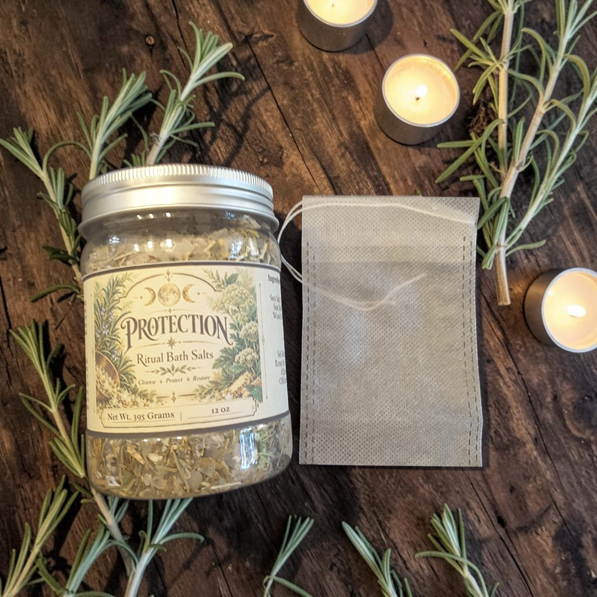protection herbal bath salts in a jar next to a muslin bag on a dark wooden surface with rosemary and candles
