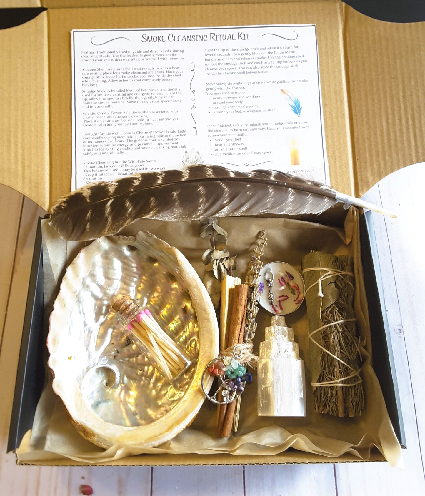 Smoke cleansing ritual kit featuring rosemary and bay leaf smudge stick, abalone shell, selenite crystal tower, candle, and botanicals
