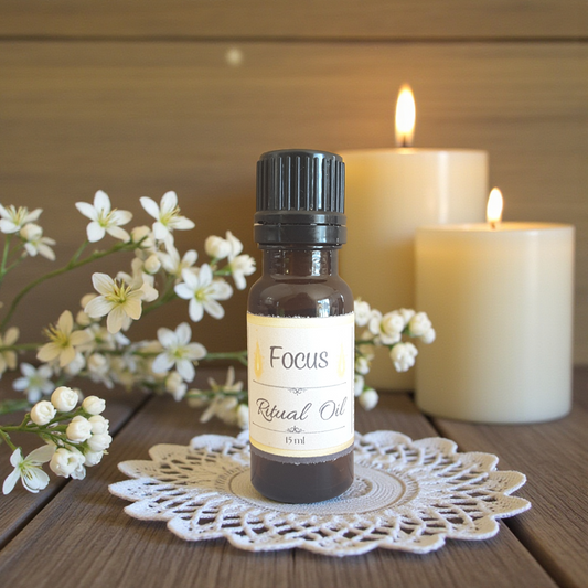 Bottle of 'Focus' ritual oil on a wooden surface with candles and flowers in the background