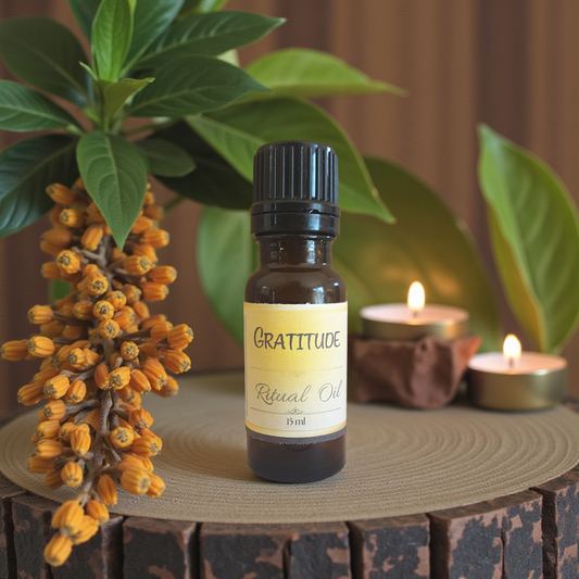 Bottle of 'Gratitude' ritual oil on a wooden surface with plants and candles in the background