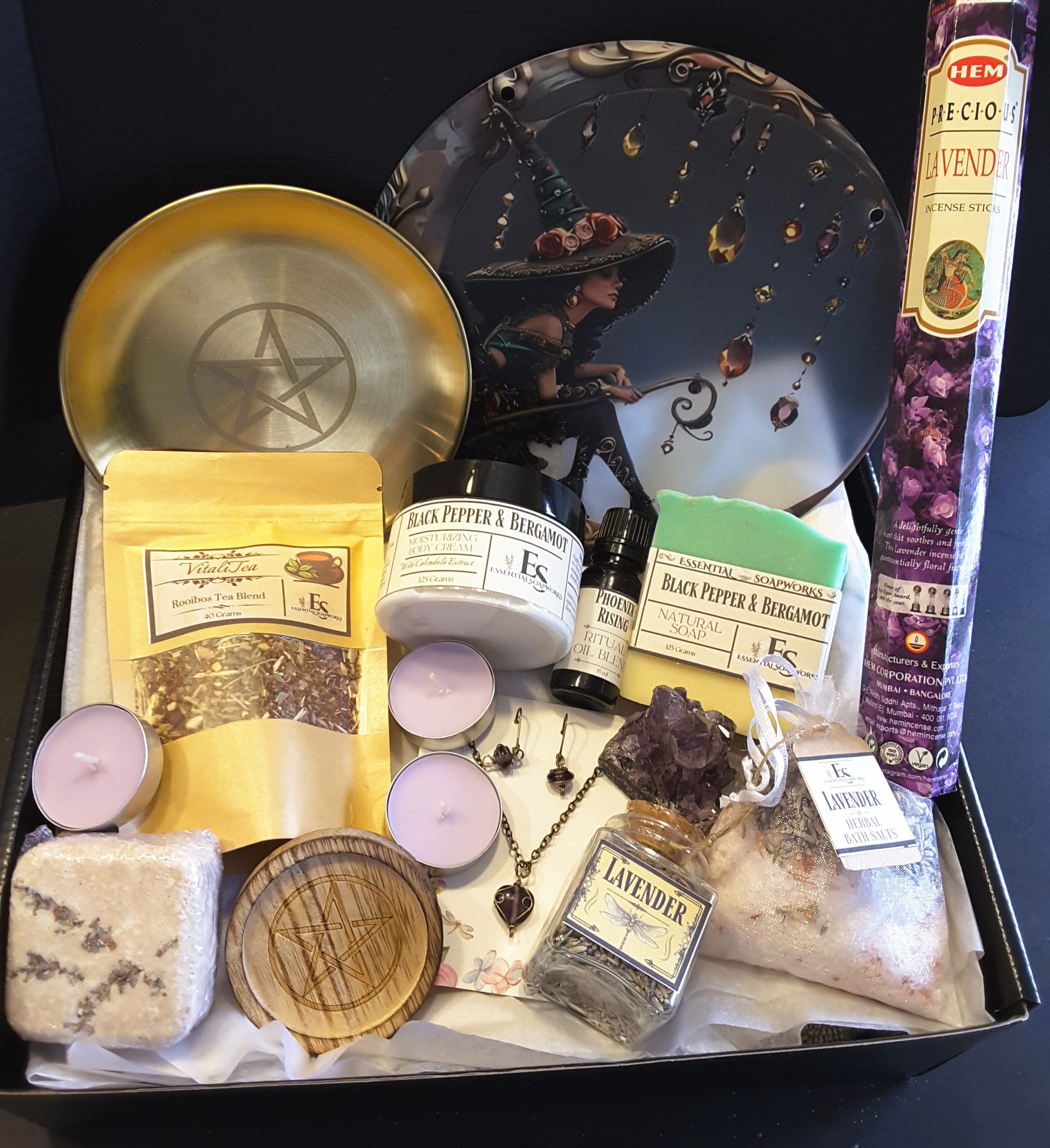 Witchy Subscription Kit including candles, a pentacle dish, and a bottle labeled 'Lavender' on a dark surface.