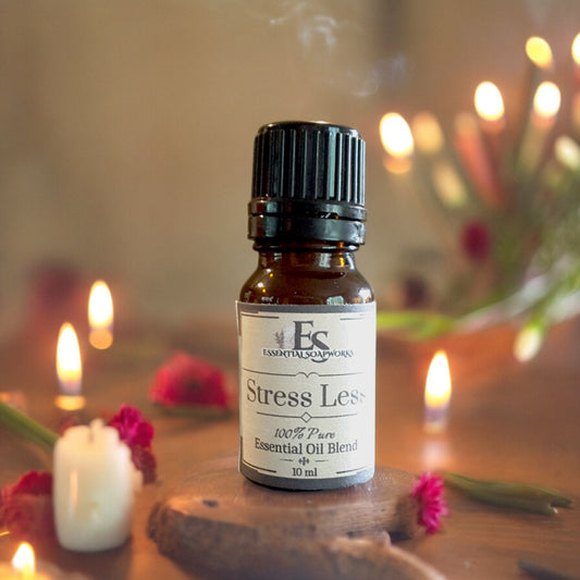 Bottle of 'Stress Less' essential oil blend on a wooden surface with candles and flowers in the background.
