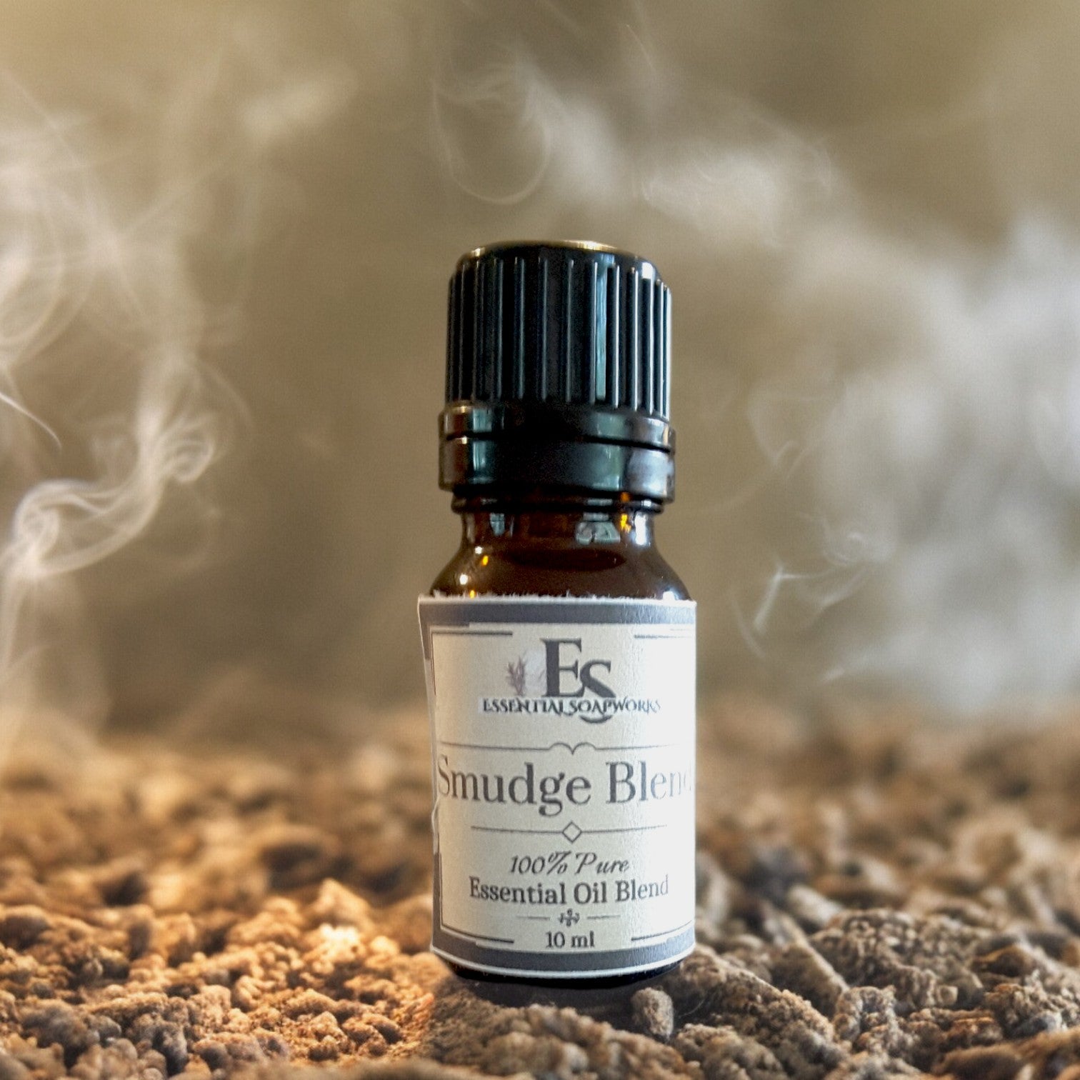 Bottle of Smudge Blend essential oil on a textured surface with smoke in the background