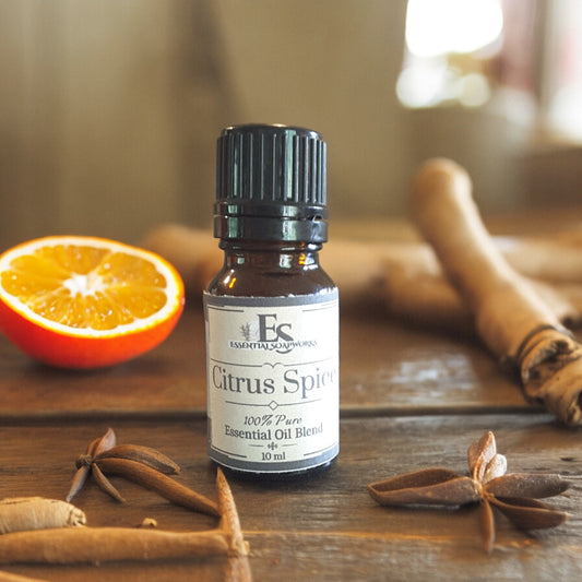 Bottle of 'Citrus Spice' essential oil blend on a wooden surface with an orange, cinnamon stick, and star anise.