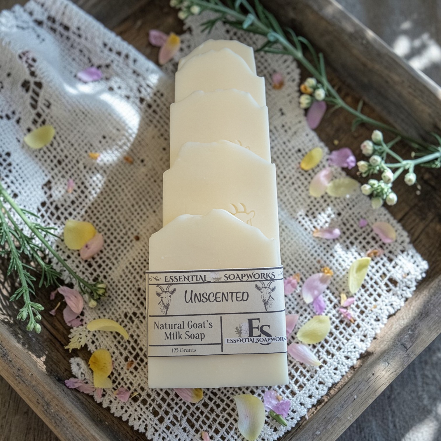 Stack of unscented natural goat's milk soap bars on a wooden tray with flowers