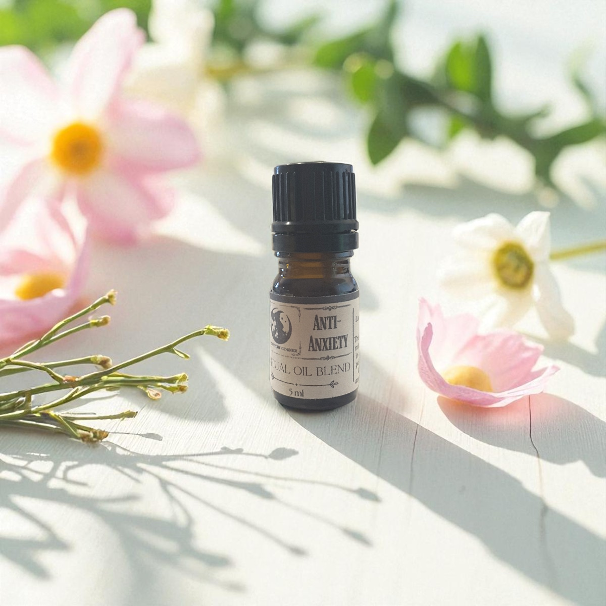 Small bottle of 'Anti-Anxiety' essential oil blend surrounded by flowers on a light surface