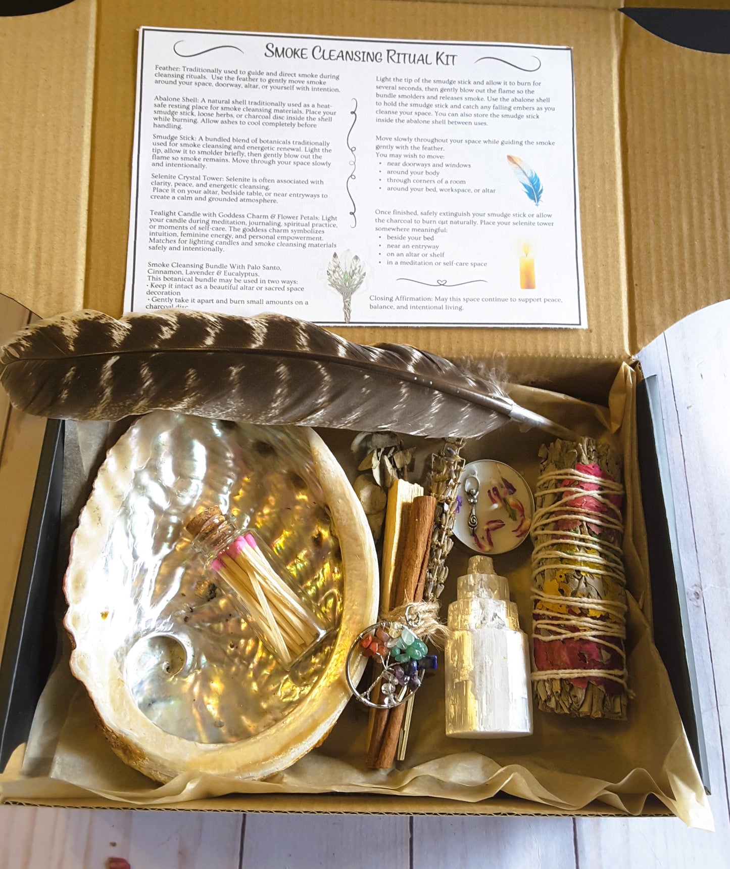 Smoke cleansing ritual kit featuring white sage smudge stick, abalone shell, selenite crystal tower, candle, and botanicals