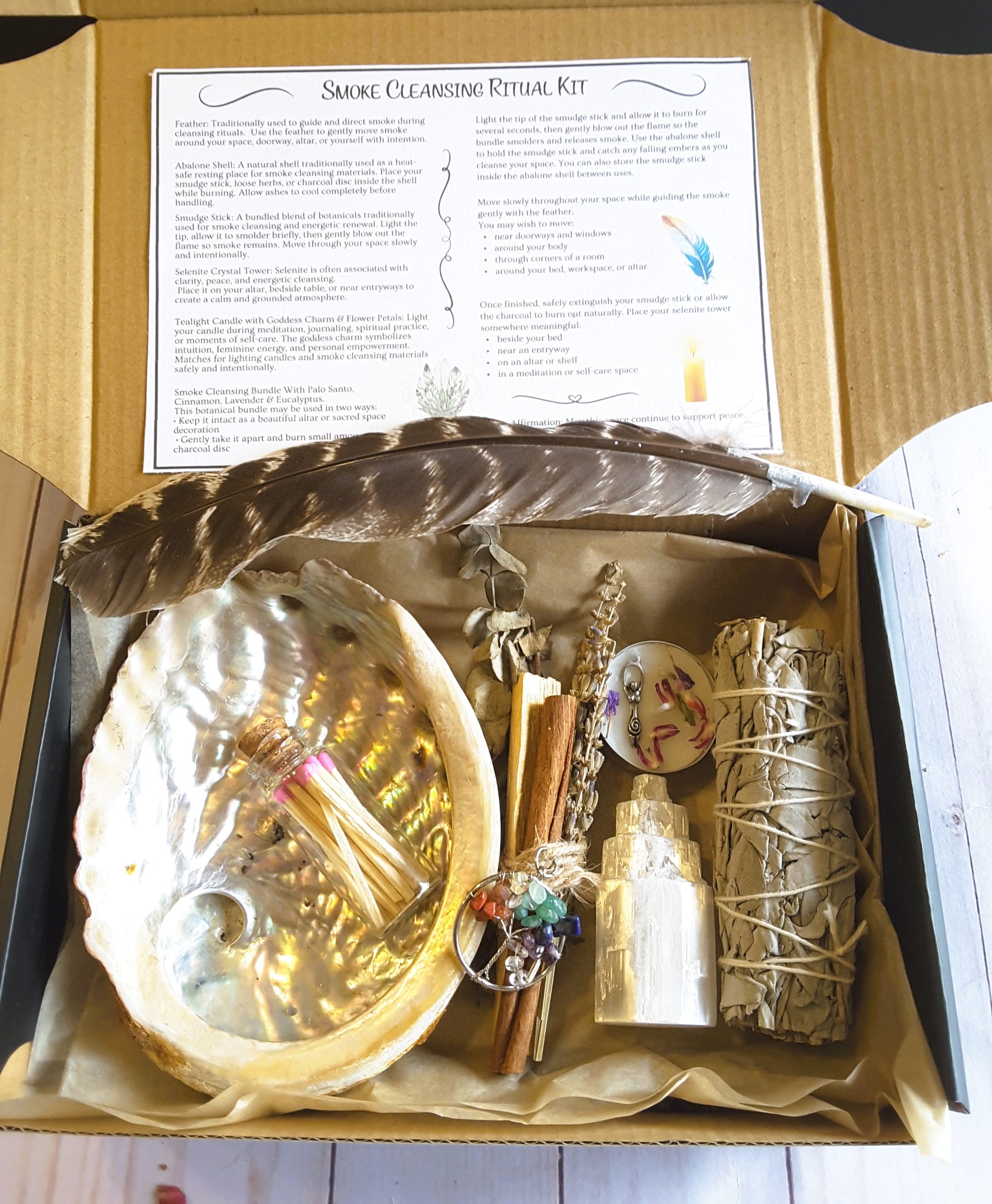 Smoke cleansing ritual kit featuring white sage smudge stick, abalone shell, selenite crystal tower, candle, and botanicals