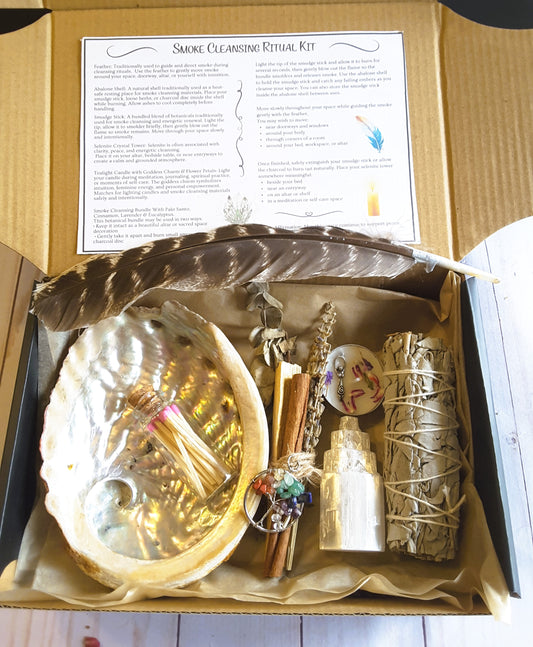 Smoke cleansing ritual kit featuring white sage smudge stick, abalone shell, selenite crystal tower, candle, and botanicals